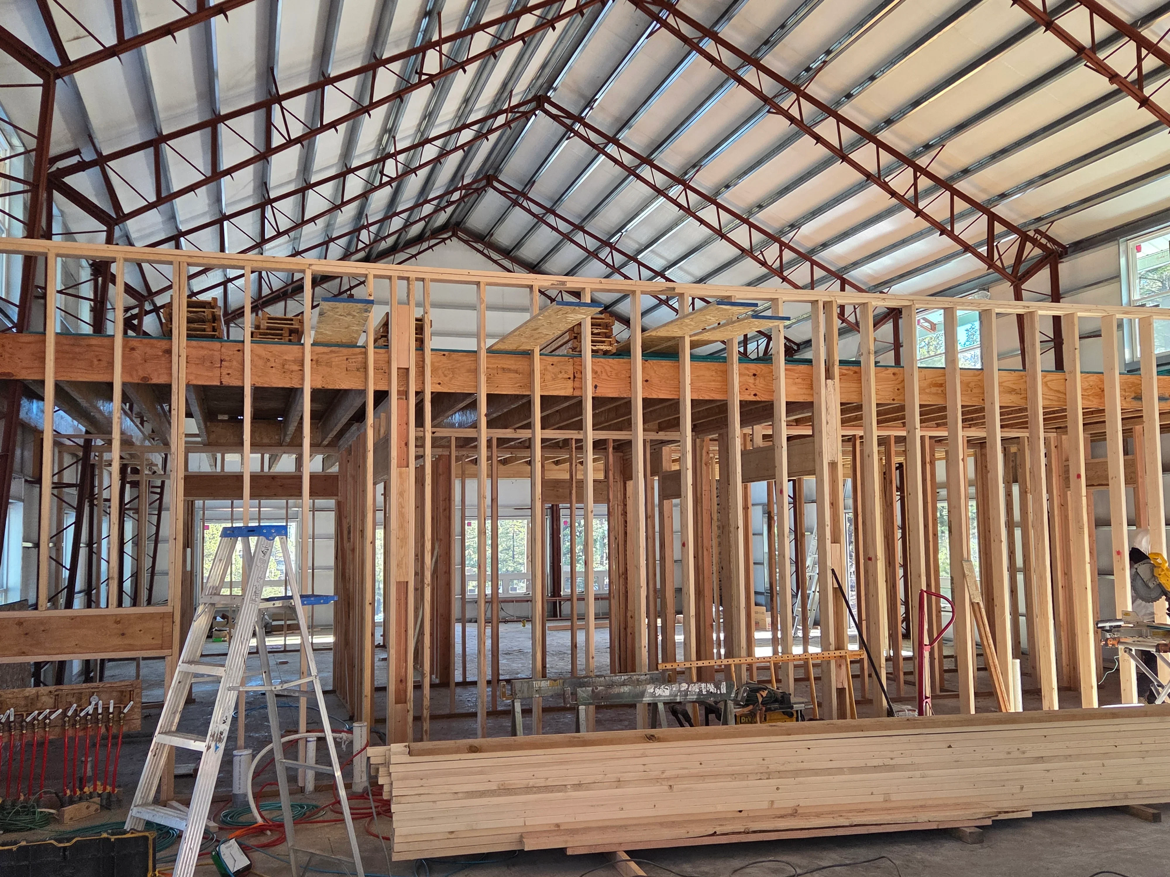 Interior wood framing with studs and headers under metal building roof structure