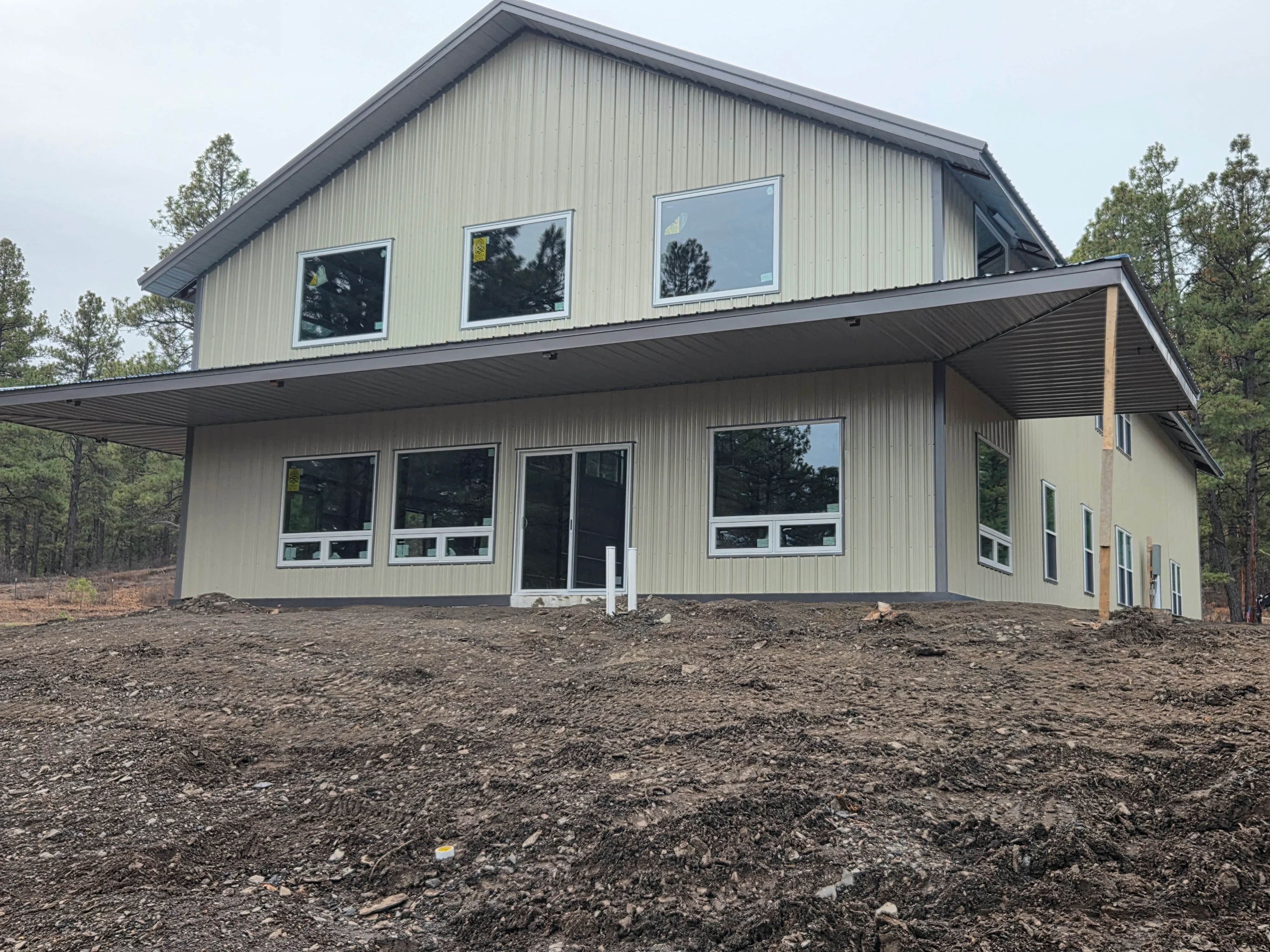 Modern metal building home with corrugated steel siding, gabled roof, and large aluminum windows