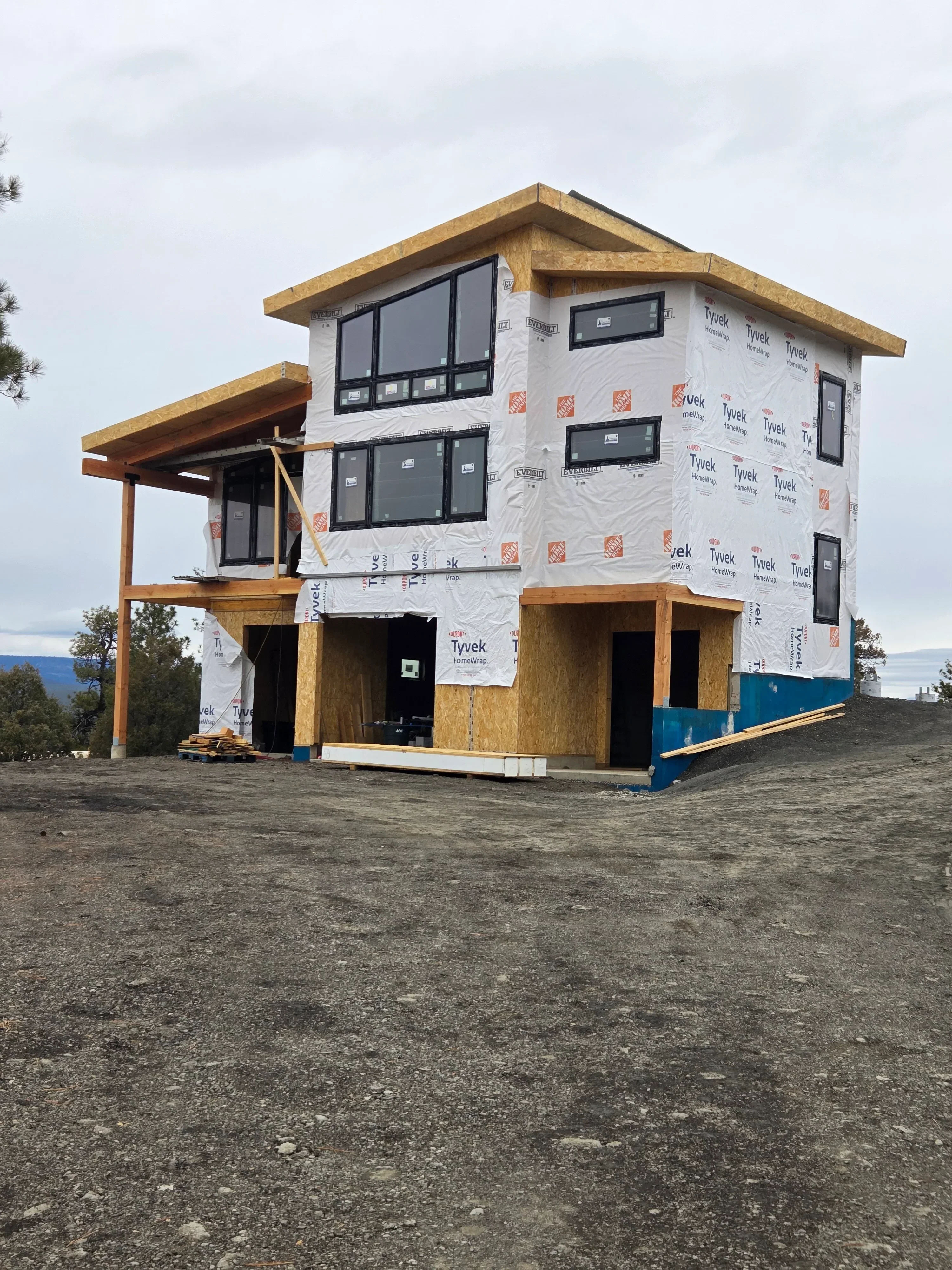 Wood-framed residential structure with window openings, floor joists, and Tyvek weather barrier